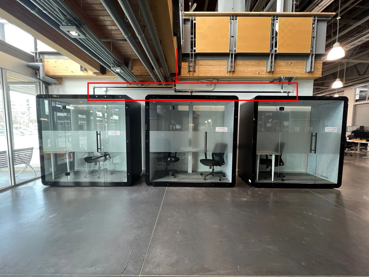 Three SensPods installed against a wall, with the building's overhead sprinkler pipe running above them highlighted.